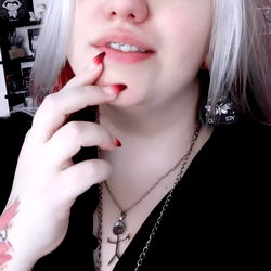 A Tattooed Woman in a White Shirt with Red Nails and a Necklace