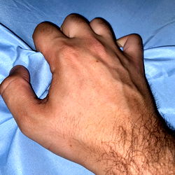 Hand reaching over the edge of a bed