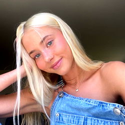 Blonde Woman with Light Blue Denim Jumpsuit and Tank Top, Sitting and Leaning on Her Elbow