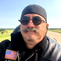 A bearded biker in a blue bandana and sunglasses