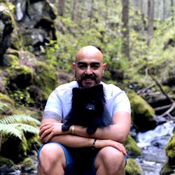 Smiling Man Hugging Dog in Forest Setting