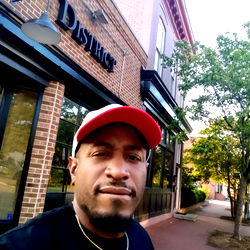 Street-side Selfie of Man in Red Hat