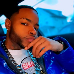 Stylish young male posing in blue jacket with chain and chain accessory