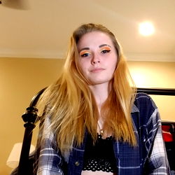 Rose, a young woman with blonde hair and blue eyes, posing confidently in front of a camera.