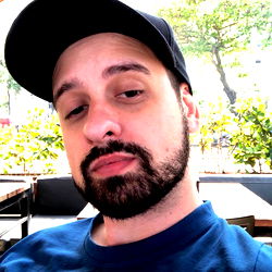 Rodrigo Brocchi - Casually Dressed Man with a Beard and Mustache, Sitting at an Outdoor Cafe