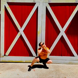 2much's Playful Pose in Front of a Red Barn Door