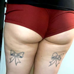 OnlyFans model Jace showcasing unique, short shorts with bow and tattoo