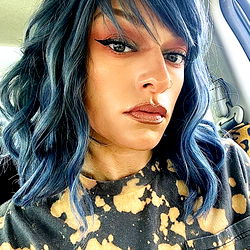 Cassie, a stylish individual with blue hair and dramatic makeup.