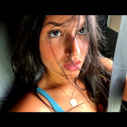 A young woman with a strong gaze and a necklace, set against the backdrop of her car