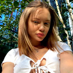 A young woman in an outdoor setting, taking a selfie.