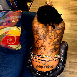 Outta mind, outta state tattooed model in strong pose on couch