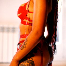 Vibrant and alluring model Bonny Boombox in a striking red corset and matching accessories, from Madrid, Spain. A vision of confidence and elegance.