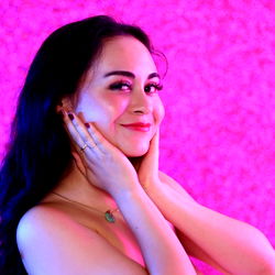 Amélie Chérie, a model from Germany, captured in a stunning photo with vivid pink lighting.