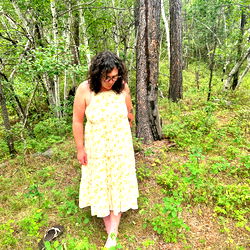 Woman in a Yellow Flower Dress Standing in the Woods