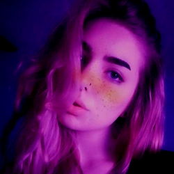 Kait, a beautiful young woman with striking blue eyes, is the main subject of this image. She's captured in a candid moment, her face partially obscured by an intriguing black and white filter that adds depth to the photograph.