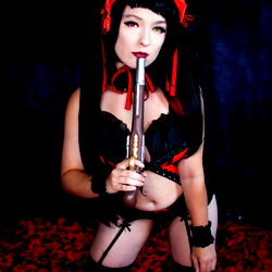 Red-haired cosplay model with a dark outfit and gun prop