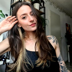 Alexandra, a tattooed beauty posing with hand on hip