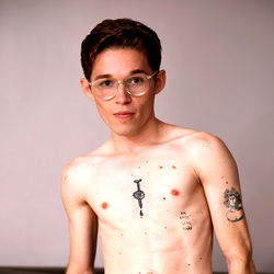 Alemãozinho, a young model with tattoos and glasses.