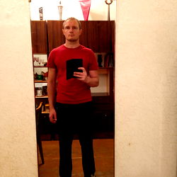 Anton Anderson in a red shirt, standing in front of a mirror