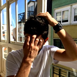 A young man adjusting his hair from behind in a candid moment.