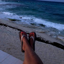 A woman relaxing on a beachside patio during sunset, with the ocean in the background.