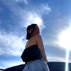 A Model Posing Against the Sun with a Vehicle in the Background