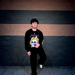 Tim, a young adult male, standing against a brick wall with a punk rock style vibe.