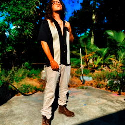 A young man stands confidently in a backyard setting.