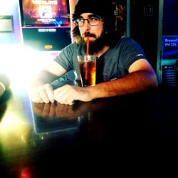 Man in Glasses, Sitting at Bar, Holding Beverage