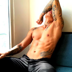 Stylish Model Andrew Sabaj in Colombia - Fashionable Shoot on Sofa with Light Blue Tattoo