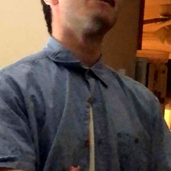 A young man in a relaxed pose with his hand on his hip.