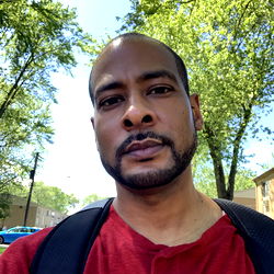 Man in Red Shirt, Black Backpack on Campus Walkway
