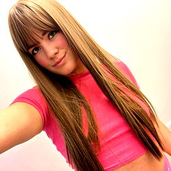 Leona, a model with long hair and a pink top, smiling at the camera.