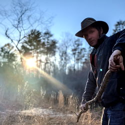 A man holding a walking stick in a wooded area