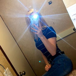 A young woman posing in a bathroom mirror