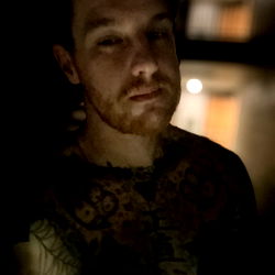 Contemplative Tattooed Man in Dim Lighting