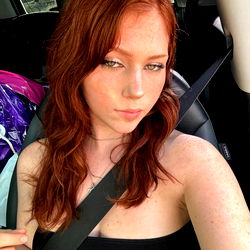 Red-headed model posing in a car