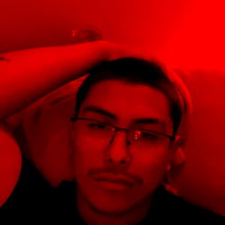 A young man posing in a dimly lit room