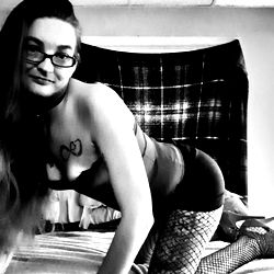 Ann in a revealing fishnet bodysuit posing for an OnlyFans photo