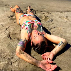 Tattooed Female Model Resting on Beach