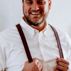 Handsome man in a suit, standing confidently against a white wall