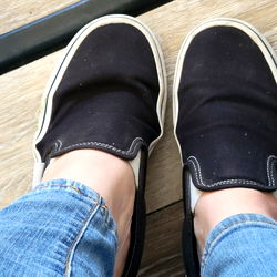 Sage69 Slip-On Shoes - Model Photo: A Close-Up of Blue Jeans and Black Shoes with White Trim