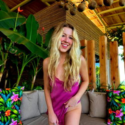 Model Nikki in a vibrant purple robe, outdoors on a patio