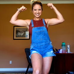 A Strong and Confident Woman Pumping Iron in a Denim Overalls