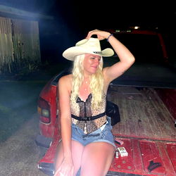 Faanccyy, a Louisiana model, strikes a pose with a cowboy hat and a pickup truck in the background.