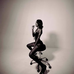 A OnlyFans Model Sitting on a Chair in Black Lingerie