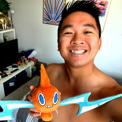 Model Showcasing Toy and Shirtless, Smiling in Background