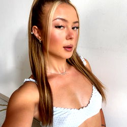 Valerka, the OnlyFans model, poses in a white crop top with high ponytail and tattoos