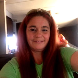 Shannon, a red-haired woman with long hair in a room, taking a selfie.