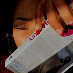 A woman holding a pack of cigarettes and focusing intently on its contents.